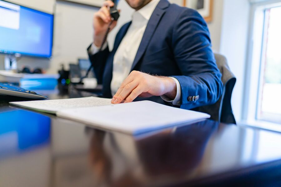 Avocat la birou, cu un dosar deschis în față și telefonul la ureche.