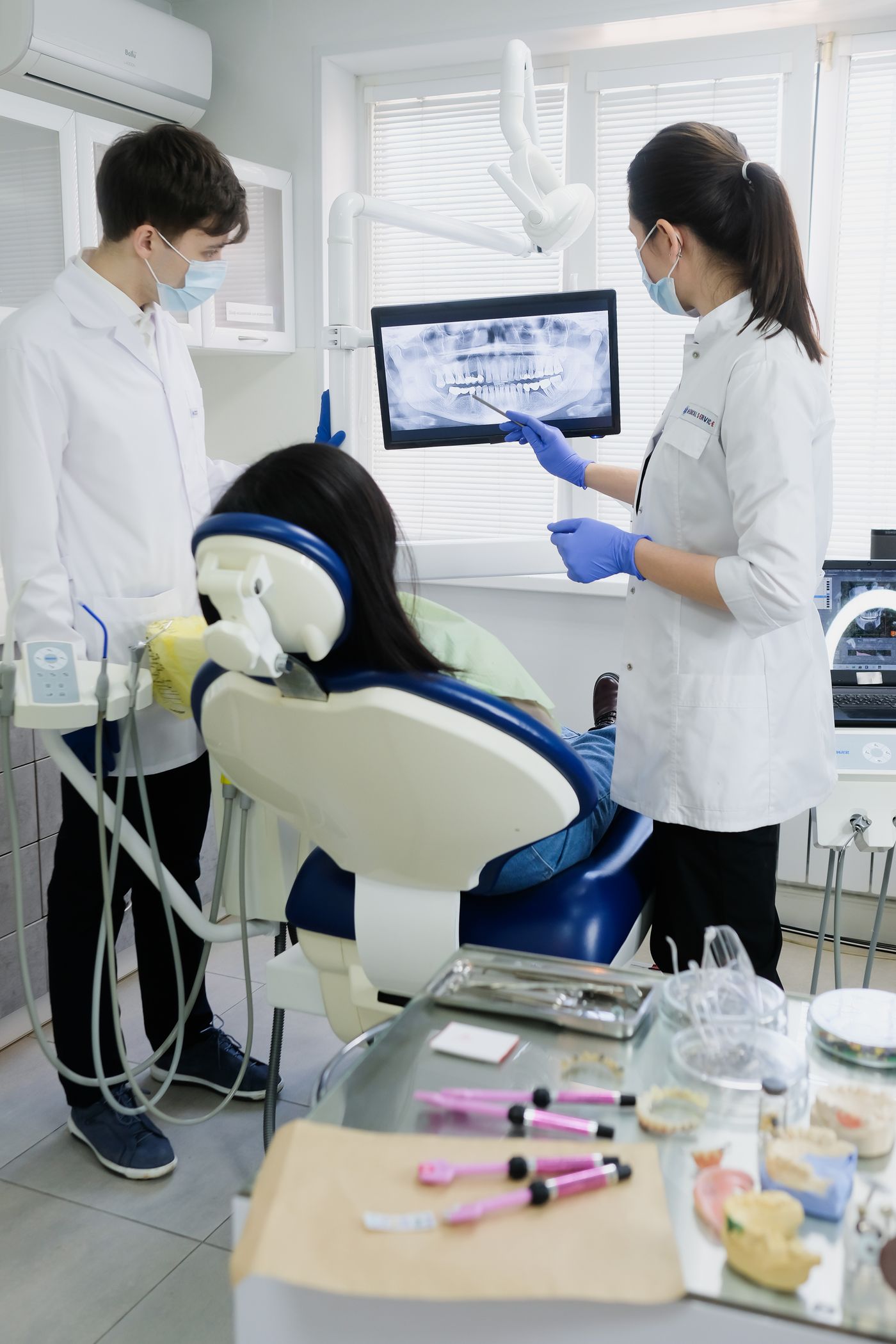 Doi medici stomatologi se uită la o radiografie digitală pe ecranul din cabinet.