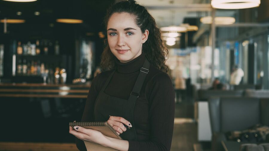 Ospătară cu tabletă în mână, în sala unui restaurant.