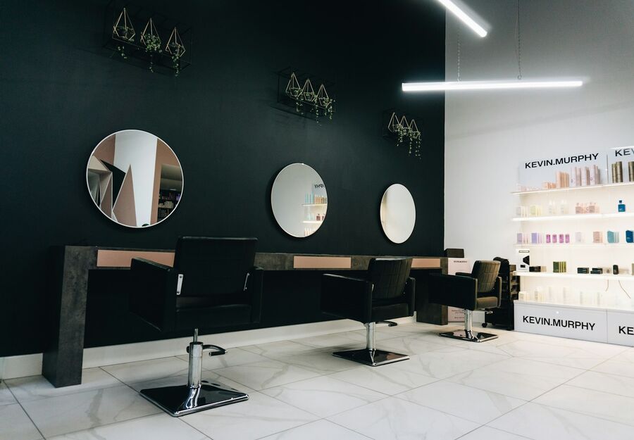Salon de înfrumusețare cu oglinzi rotunde și rafturi de produse.